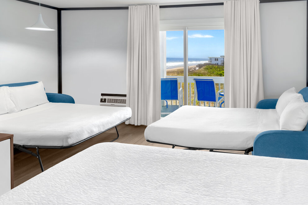a room with white beds and blue chairs